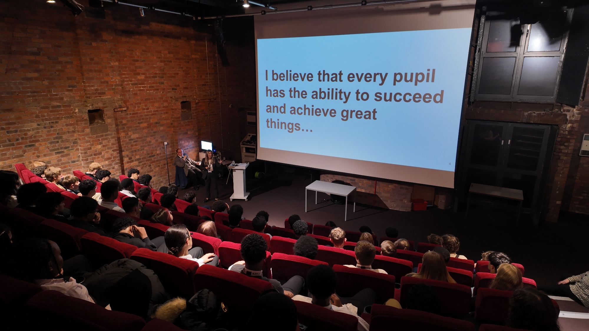 Image of sixth form students sat in front of a presentation slide delivered by sixth form staff